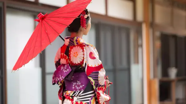 Woman in traditional colorful kimono holding red parasol in Japanese setting